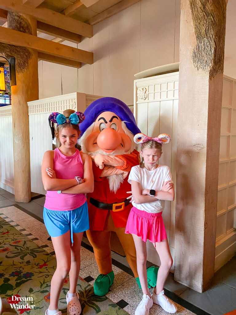 Storybook Dining at Artist Point image of 2 girls with Grumpy, one of the Seven Dwarfs